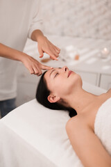 Crop female therapist doing acupressure face massage to client