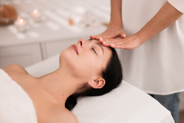 Obraz na płótnie Canvas Crop anonymous masseuse doing face massage to female customer in salon
