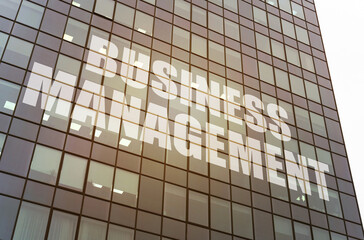 Plakat On the glass surface of the business center there is an inscription - BUSINESS MANAGEMENT