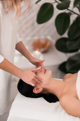 Crop masseuse treating client during face massage