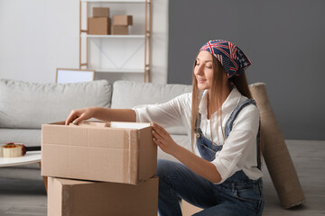 Young woman with cardboard boxes in living room on moving day