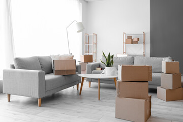 Cardboard boxes with table and sofas in living room on moving day