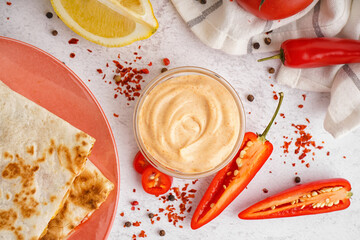 Glass bowl of tasty chipotle sauce and spices on light background