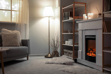 Interior of modern living room with fireplace, burning candles and shelving units