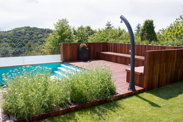 Poolside decking in green garden with nature landscape scenery view on background
