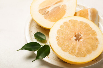 Plate with pomelo fruit and slices on white background, closeup