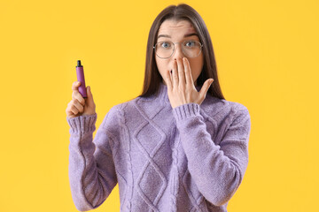 Shocked young woman with disposable electronic cigarette on yellow background