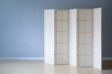 Beige folding screen near grey wall