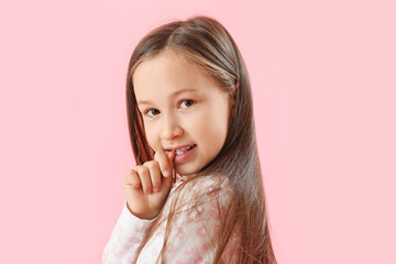 Little girl biting nails on pink background, closeup