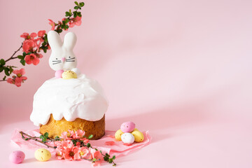 Easter cake and colorful eggs and Easter decorative bunny on a pink background with spring cherry blossoms and copy space. Easter Ukraine orthodox sweet bread.Easter card concept.