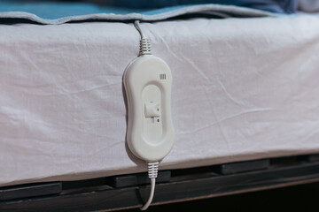 Electric heating pad with controller on bed at night, closeup © Pixel-Shot