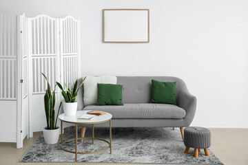 Interior of living room with folding screen, sofa and table near white wall