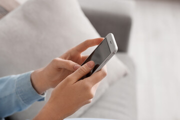 Young woman using smartphone at home, closeup