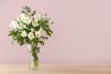 Vase with beautiful alstroemeria flowers on table against color wall