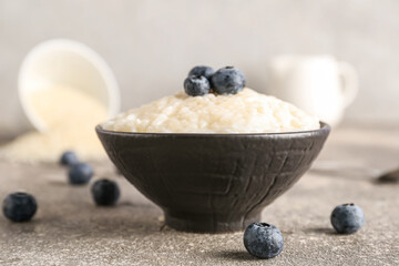 Bowl with delicious rice pudding and blueberry on grey table
