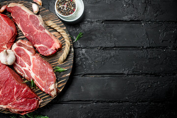 Raw meat. Pork and beef steaks on a tray with spices and rosemary sprig.