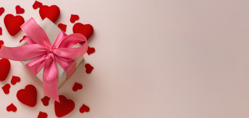 Valentine's day background. Pastel banner with red hearts and gift with ribbon. Place for text.