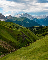 Fototapeta na wymiar Alpine landscape with mountains and green meadows and a mountain range in the background. Italian Alps, Dolomites, Italy, Europe. Tourism and travel concept.