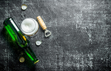 Beer in a glass and a glass bottle with opener.