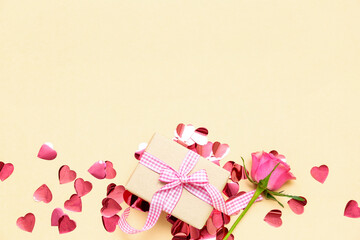 Beautiful composition with gift box, confetti and rose flower on color background. Valentine's Day celebration