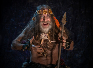 A bearded man with long gray hair holds a rat in his hands and looks at it