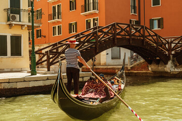 Authentic gondola on the Venice Grand Canal on a summer day, Venetian street retro aesthetic, vintage wooden bridge over the canal, real old Venetian houses. Italian architecture and landmarks