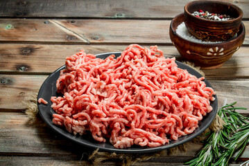 Raw minced meat in a plate with spices and herbs .