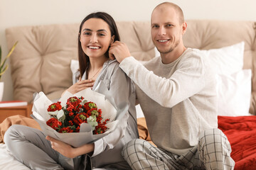 Young man putting necklace around his wife's neck in bedroom on Valentine's Day