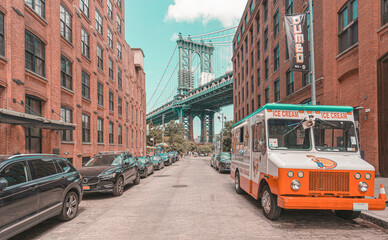 Manhattan Bridge seen from Brooklyn in narrow alley enclosed by two brick buildings on a sunny day in Washington street in Dumbo, Brooklyn, NYC - obrazy, fototapety, plakaty