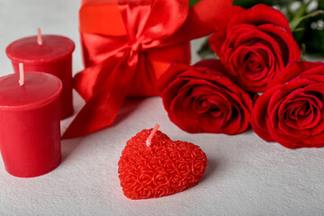 Candles, rose flowers and gift box on light background, closeup. Valentine's Day celebration