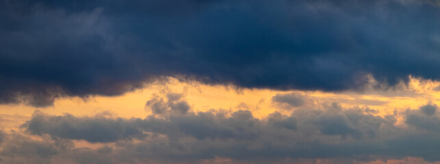 Dark storm clouds illuminated by the bright evening sun, panorama