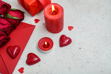 Composition with burning candles, envelope and rose flowers on light background. Valentine's Day celebration