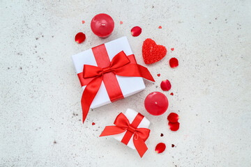 Composition with gift boxes, beautiful candles and rose petals on light background. Valentine's Day celebration
