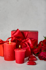 Burning candles and gift boxes on light background. Valentine's Day celebration