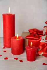 Burning candles, gifts and confetti on light wooden table. Valentine's Day celebration