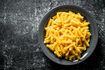 Dry fusilli pasta in a bowl.