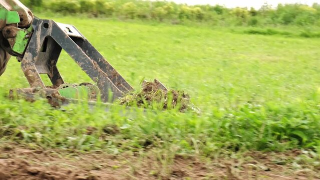 Land work by the territory improvement. Small tractor with a ground leveler for moving soil, turf. A green mini skid steer loader clear the construction site. Machine for agriculture work. Copy space.