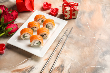 Plate with sushi rolls, chopsticks, gifts and roses on grunge background. Valentine's Day celebration