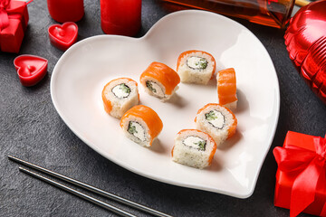 Plate with sushi rolls, chopsticks and candles on dark background, closeup. Valentine's Day celebration