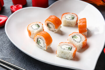 Plate with sushi rolls on dark background, closeup. Valentine's Day celebration