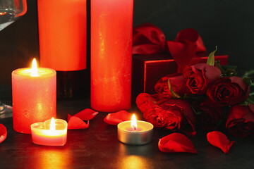 Burning candles and beautiful rose flowers on dark background. Valentine's Day celebration