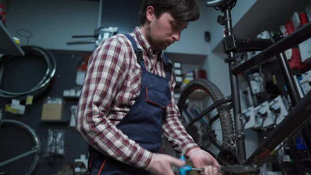 Bike repairman unscrews the bottom bracket of the front crankset with a specialized tool in workshop. Maintenance and service concept. Bicycle crank set. Remove a part of the vehicle for service. 