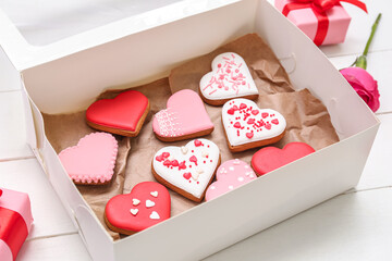Box with tasty heart shaped cookies on light wooden background, closeup. Valentine's Day celebration