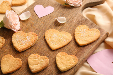Wooden board with sweet heart shaped cookies and rose flower, closeup. Valentines Day celebration
