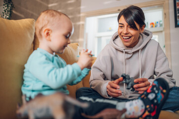 Mom and toddler son playing with dinosaurs toys at home on the couch
