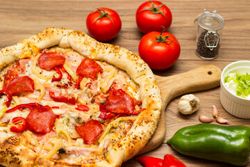 Sausage and vegetable pizza served on round wooden board