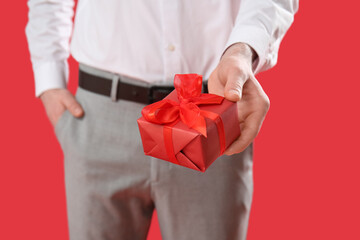 Man holding gift on red background. Valentine's Day celebration