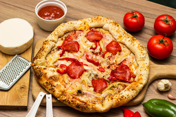 Sausage and vegetable pizza served on round wooden board