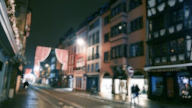 Visiting Alsace Strasbourg Christmas Market  - Defocused ultrawide blur scene of city in blue neon colorful lights decorated for Christmas winter holidays - silhouette of pedestrians walking 