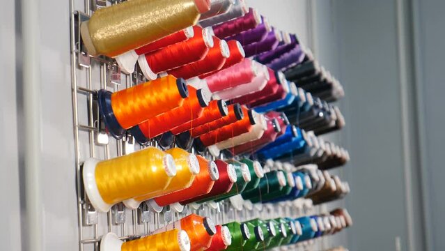 Rows spools of thread of different colors in industrial sewing factory. Textile Industry at Garment Manufacturers. Weaving machine for garment industry. Sewing workshop or tailoring factory. 4 k video
